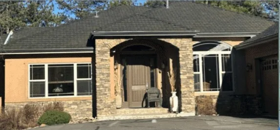 Stucco home with a stone entry arch beneath a dark low-slope roof